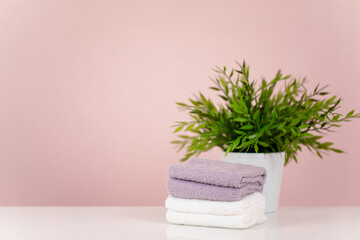 Fototapeta na wymiar The concept of a spa salon. A stack of towels and a potted flower. Pink background. Copy space.