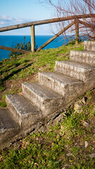 Escalera de piedra en loma de hierba verde junto al mar azul