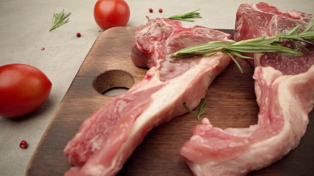 Raw lamb racks on wooden board with spice and rosemary