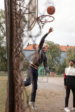 Teenager throwing ball into basketball hoop