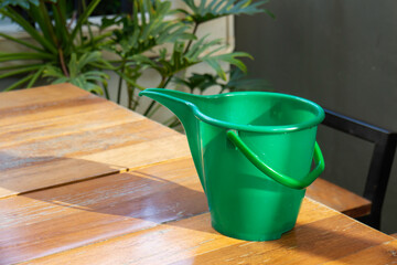 Green watering can on wooden table