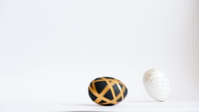 Egg are rolling on the white table, knock each other. Easter golden decorated eggs isolated on white background. Minimal easter concept. Happy Easter card