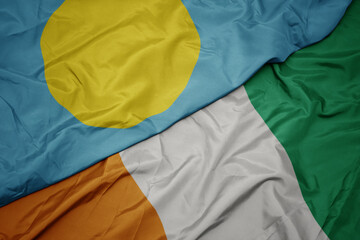 waving colorful flag of cote divoire and national flag of Palau .