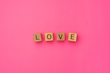 Wooden cubes with the word Love on an empty colorful pink background. Word of love are made of letters from wood for your girlfriend, boyfriend, wife, husband, for Valentine's Day greeting romantic