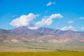 Colorful alpine scenery with big multicolored mountains under blue sky in sunny day. Vivid mountain landscape with great motley mountain range in sunlight. Awesome view to high variegated rocky ridge.