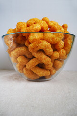 peanut flips . lots of corn sticks in peanut butter frosting in a glass round bowl on a gray light background side view