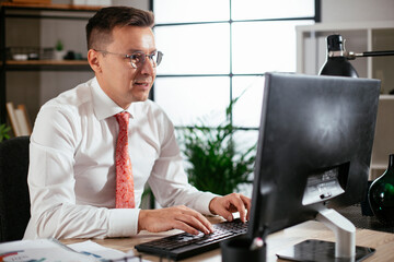 Young businessman using computer in his office. Handsome man working at his workplace.