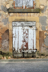 Old Weathered Wooden Door on Old Stone Building beside Street 