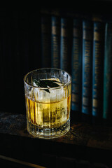A glass of cocktail stands on a bookshelf