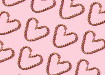 Trendy valentines day backgound with golden necklace heart and hard shadow on pink.