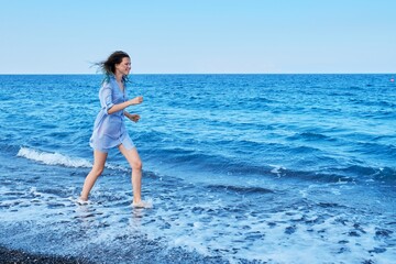 Beautiful young woman running on sea beach