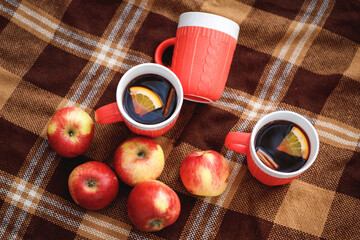 Cups with mulled wine and red apples on a blanket