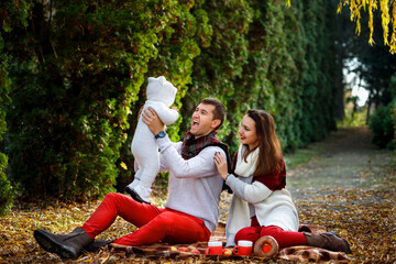 Parents play with their child in the fall in the park. Happy family having fun.