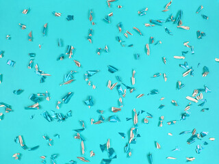 Confetti foil pieces on blue background. Abstract festive backdrop.