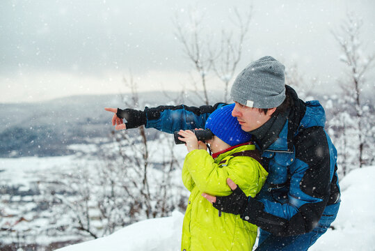 Kid looking to monocular. Family winter holidays. Father and kid having fun together on nature.