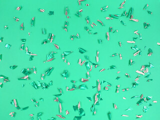 Confetti foil pieces on green background. Abstract festive backdrop.