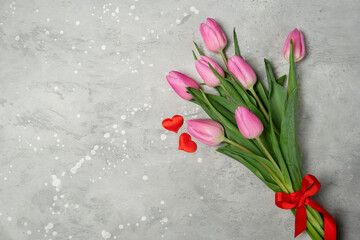 Festive background bouquet of pink tulips gifts red hearts on a gray concrete background. Top view, copy space. Valentine's day concept.