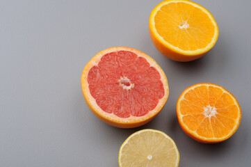 Cut in half fresh lemon, grapefruit, orange, tangerine on a gray background, top view. Citrus juice ingredients, food background