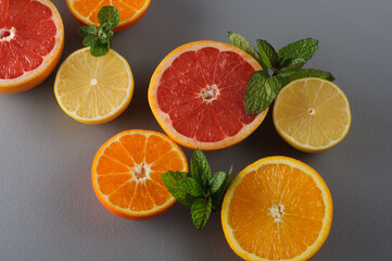 Fresh citrus and mint cut in half on a gray background. Juicy grapefruits, tangerines, lemons, oranges.Citrus juice ingredients, food background