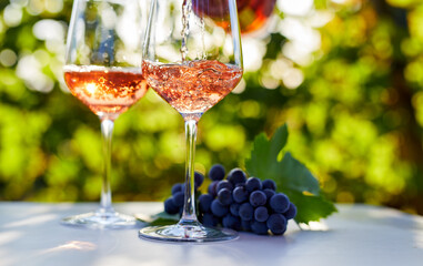Pouring rose wine into glasses on a table outside in a vineyard - 410115053