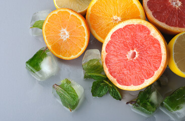 Fresh citrus and mint cut in half on a gray background. Juicy grapefruits, tangerines, lemons, oranges. Preparation of cold juices and drinks.Citrus juice ingredients, food background