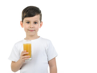 A 6-year-old boy in a white T-shirt holds a glass with citrus juice on a white background. Isolated background. Baby loves orange juice. Positive emotions. healthy food for children, schoolchildren