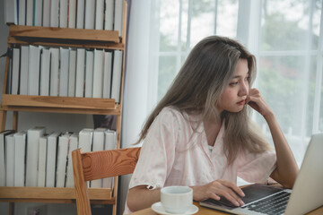 Lazy bored asian woman using laptop in the morning.