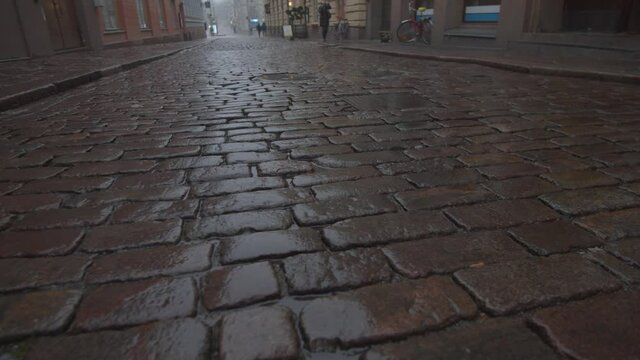 Tracking shot across old traditional wet cobbled street or road