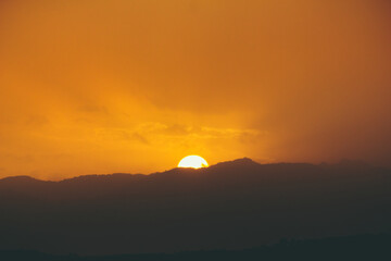 Fototapeta na wymiar Close up of a big sun falling down under the mountains
