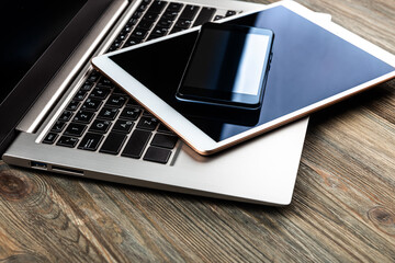 laptop with phone and tablet pc on wooden desk