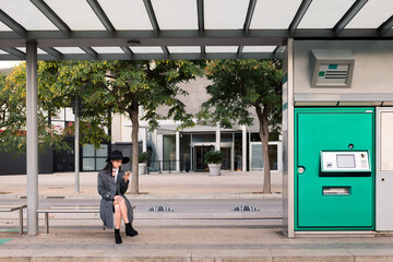 asian woman consulting phone while waiting the bus