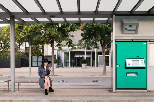 asian woman consulting phone while waiting the bus - Powered by Adobe