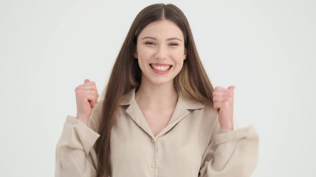 A happy young woman is showing thumb-up gesture standing isolated over white background in studio