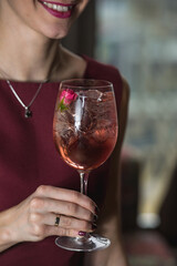 woman holds relaxing alcoholic pink coctail with a rose on top