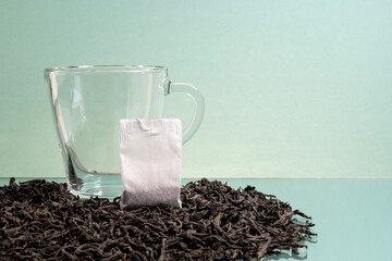 A tea bag and a glass cup are on a mirrored table. Tea bags. Black tea. Transparent cup. Advertising, copy space.