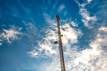 Obraz premium Telecommunication tower against the backdrop of an awesomely beautiful sky with blurry snow-white clouds