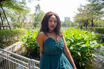 Cheerful young woman standing among tropical garden.