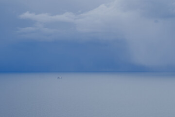 Lonely fishing boat is heading to port near weather front with clouds in sea.
