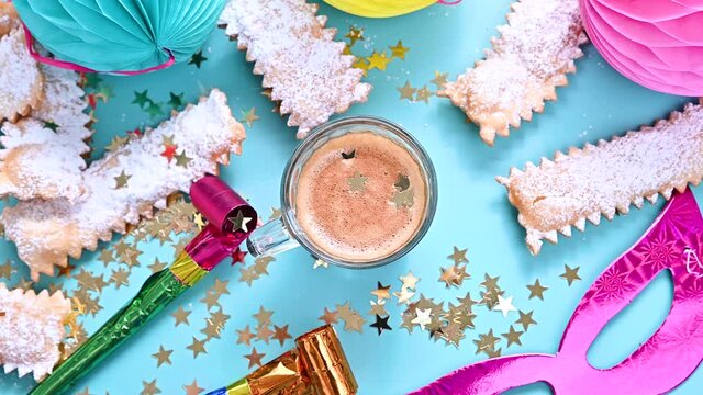 Falling confetti and sparkles . Traditional Venetian carnival and food TYPICAL. Coffee, Sfrappole or chiachiere or angel wings and aromatic coffee on a bright blue background. Copy space
