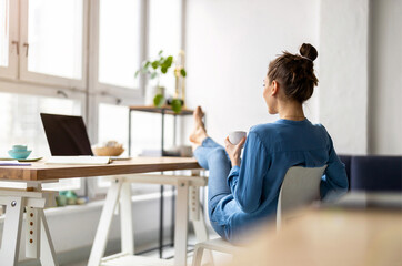 Young woman relaxing in office with her bare feet on desk 
 - obrazy, fototapety, plakaty