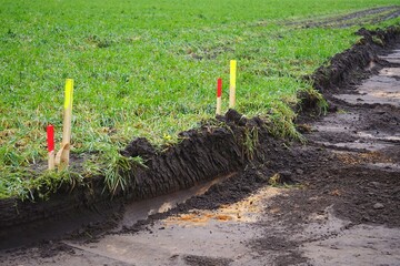 Baustelle: Holzpflöcke, Messpflöcke kennzeichnen die Grenze zwischen der ausgekofferten Baustelle...