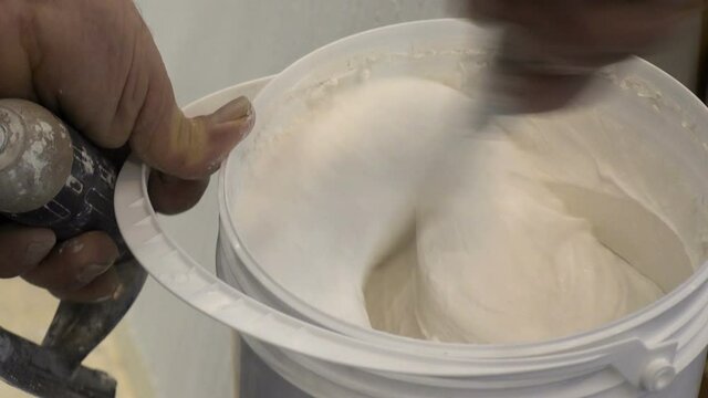 Master plasterer stirring white plaster in a bucket