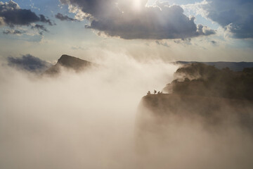 Tracker stands on the top of a mountain in the light of the sun and clouds.