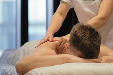 Fototapeta na wymiar Close-up of man enjoying in relaxing shoulders massage . Man relaxing on massage table receiving massage