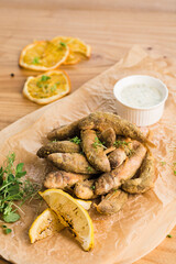 Grilled mullet with lemon and sauce on a board on a light wooden background close-up.