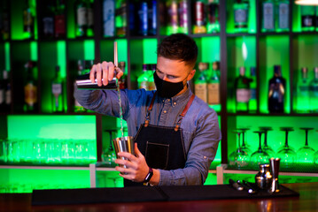 Young guy a working as a bartender while preparing cocktails in a pub
