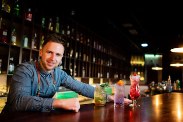 Young guy a working as a bartender while preparing cocktails in a pub