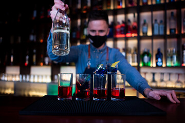 Young guy a working as a bartender while preparing cocktails in a pub