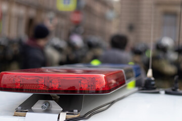 Obraz premium Police alarm siren on car close-up with blurry background with riot police.