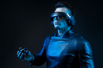 Man in futuristic costume on dark background. Guy using VR helmet. Augmented reality, virtual...